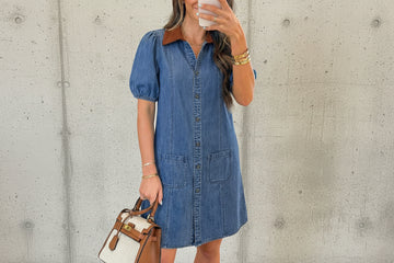 Woman taking a mirror selfie wearing a blue denim dress in a living room.