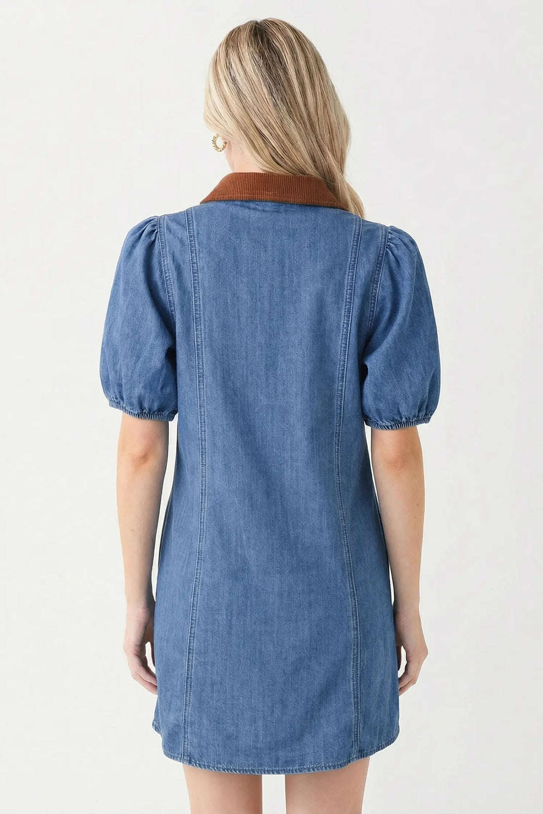 Woman taking a mirror selfie wearing a blue denim dress in a living room.