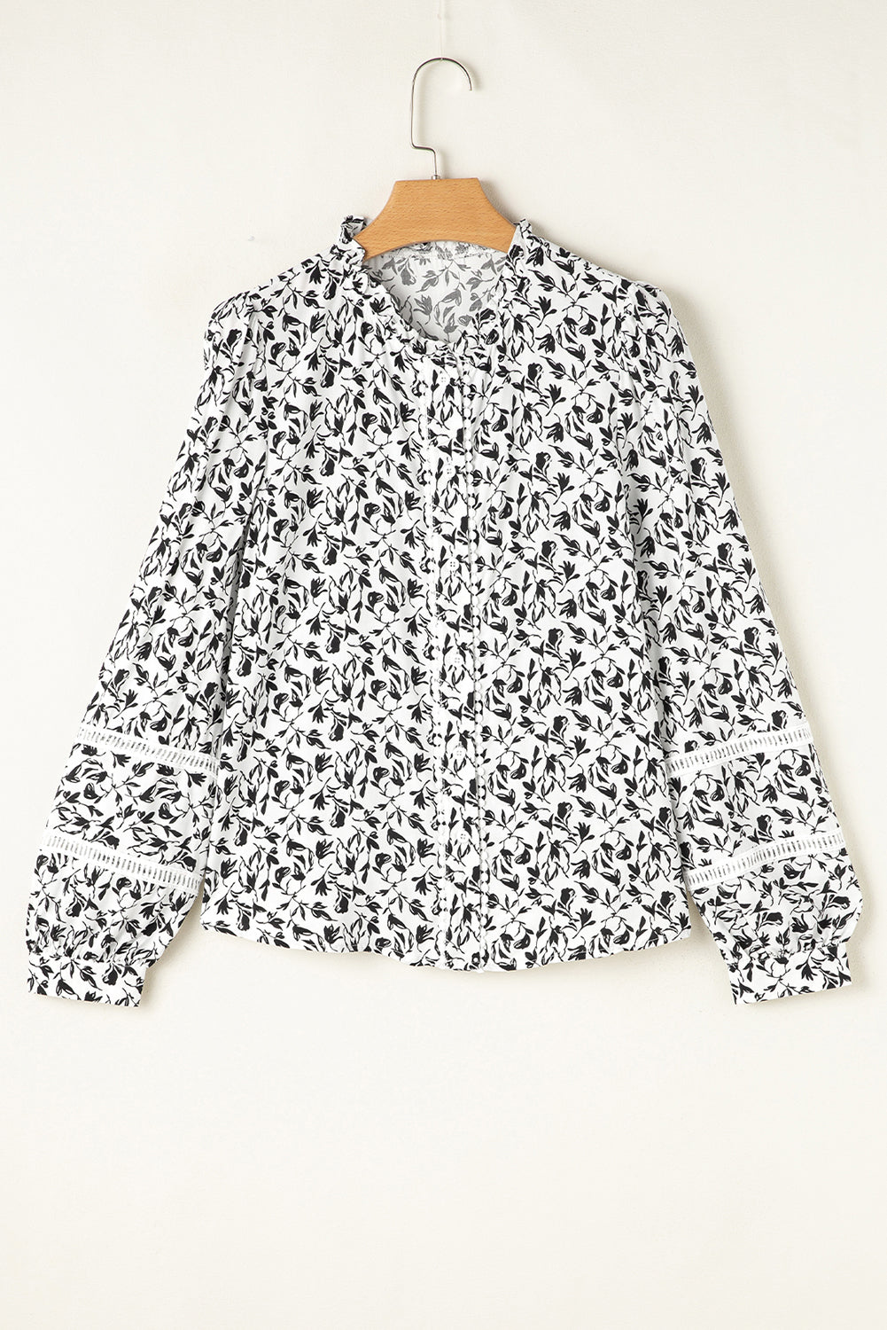 Person wearing a black and white patterned blouse with beige shorts on a gray background