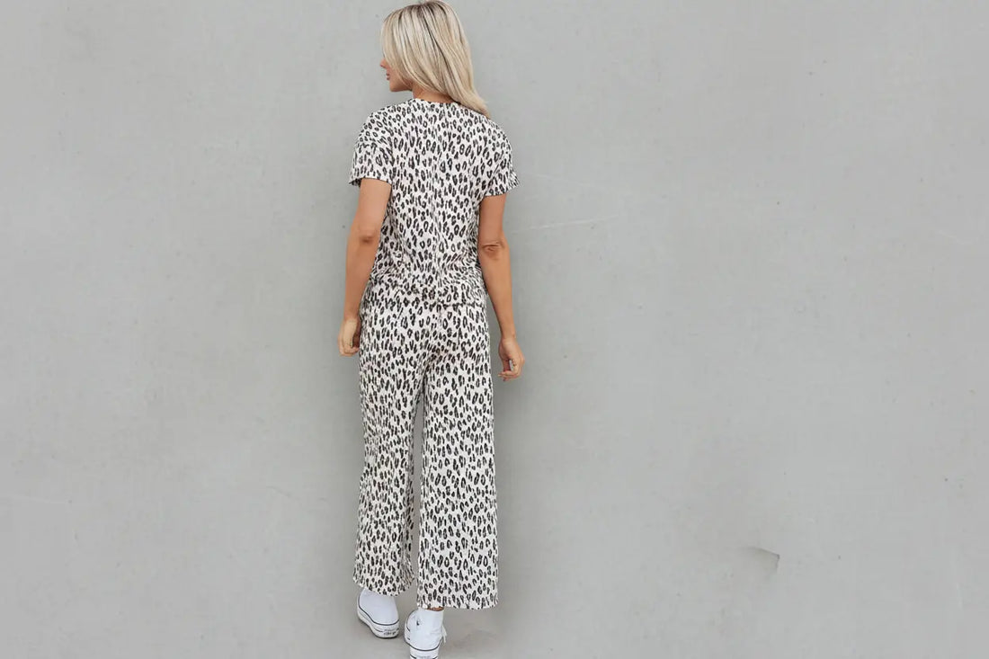 Person wearing a leopard print jumpsuit standing in front of a door with a wreath.